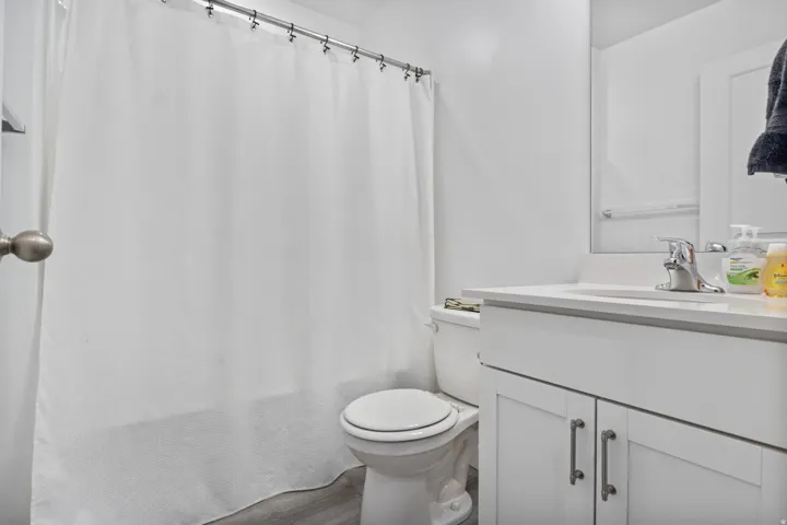 Bathroom featuring a white vanity with a chrome faucet, integrated sink, and white cabinetry with brushed nickel hardware