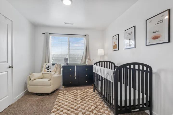 White walls complement the brown carpet flooring and window with blinds and curtains