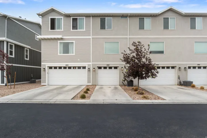Multi-level townhome featuring a light gray siding and stucco exterior with white trim