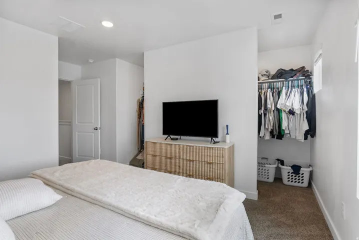 Bedroom space featuring a walk-in closet with built-in shelving, white walls, and a window