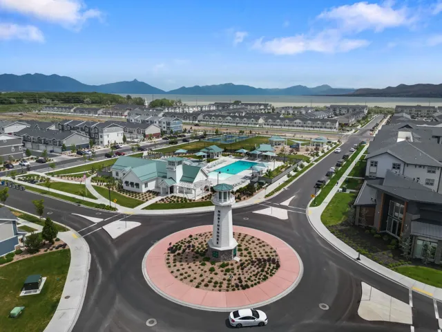 Community roundabout featuring a central lighthouse structure, surrounded by residential buildings and a recreational area with a swimming pool and green spaces