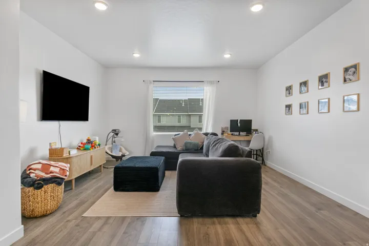 Open-concept living space featuring recessed lighting, wood-finish flooring, and a large window with blinds