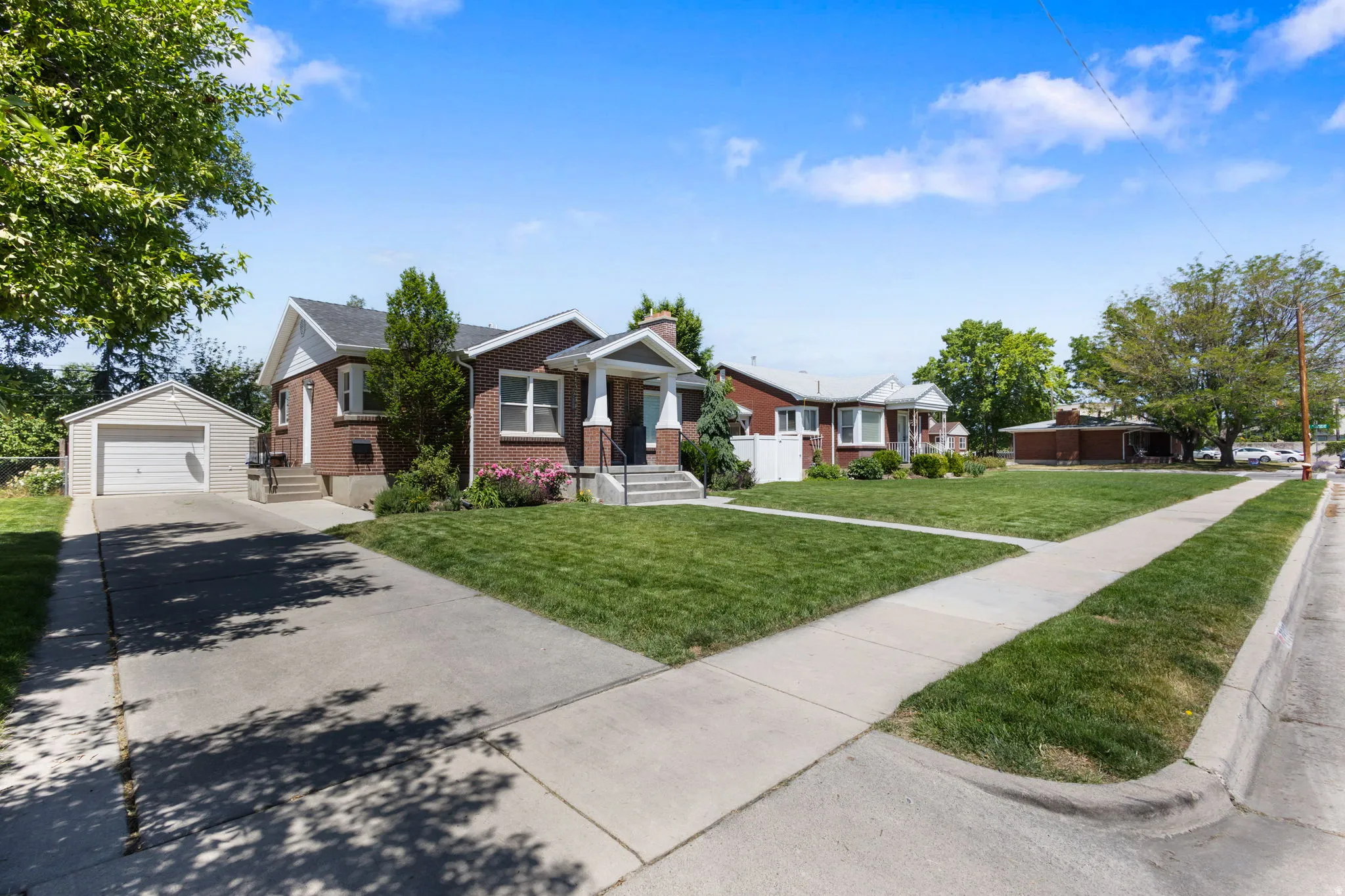 Brick exterior residence with a detached garage, concrete driveway, and front lawn