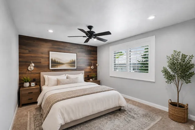 Bedroom featuring a wood-finish accent wall, light gray painted walls, and carpet flooring