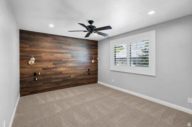 Primary Bedroom Accent wall featuring wood-finish paneling with integrated wall sconces and electrical outlets
