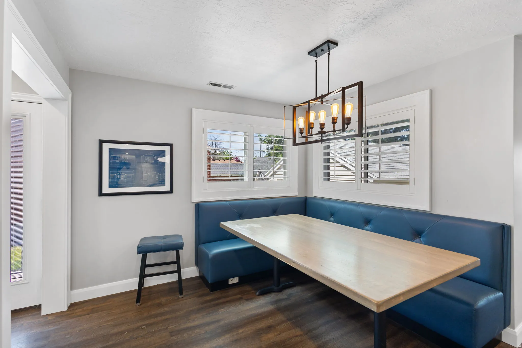 Dining area featuring a built-in blue booth, wood-finish flooring, and a linear pendant light fixture