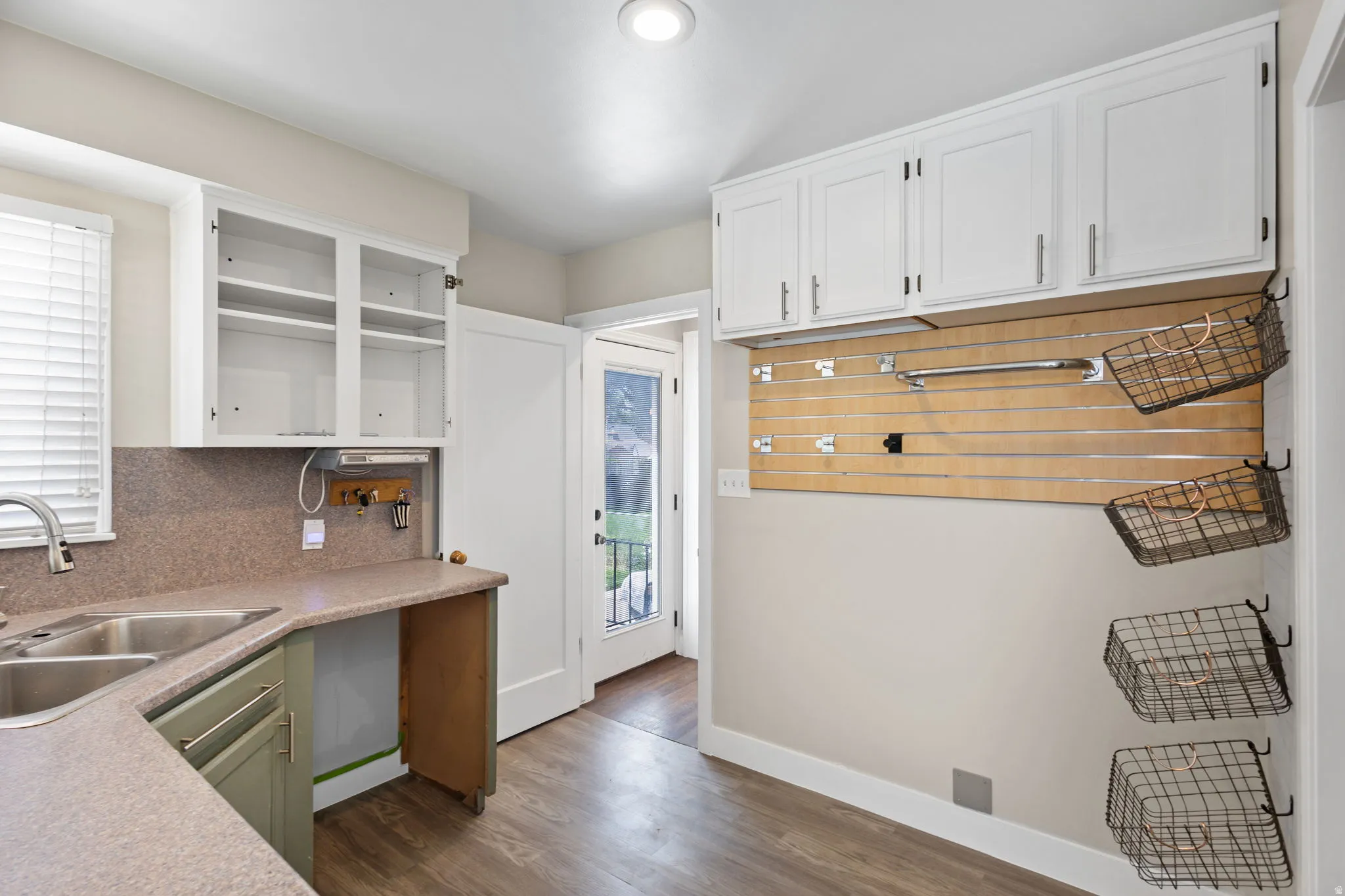 Mudroom area featuring wood-finish flooring, storage and adjustable shelving https://assets.utahrealestate.com/photos/280x210/2161055_2da27b508f97a72971e0320c13b85fdb_6a204246326b8.jpgd countertops, a double basin sink, and white upper cabinetry