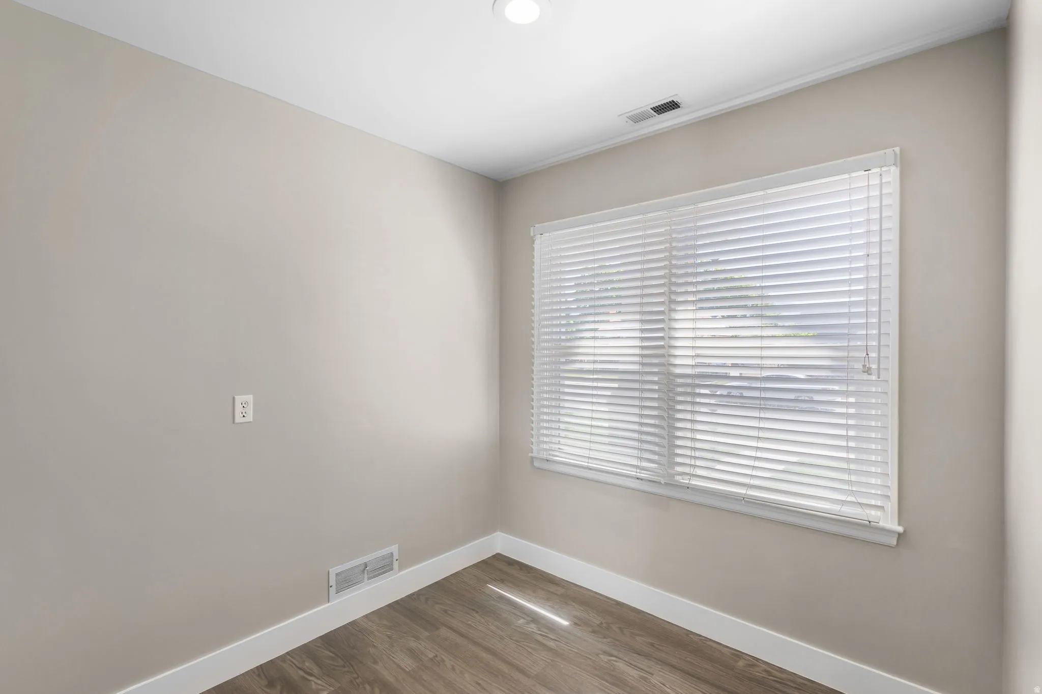 Room featuring a window with white blinds, neutral wall paint, wood-finish flooring, white baseboards, and a recessed ceiling light