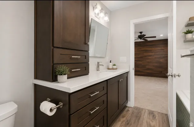 Primary Bathroom featuring dark wood-finish cabinetry, white countertop, and wood-finish flooring