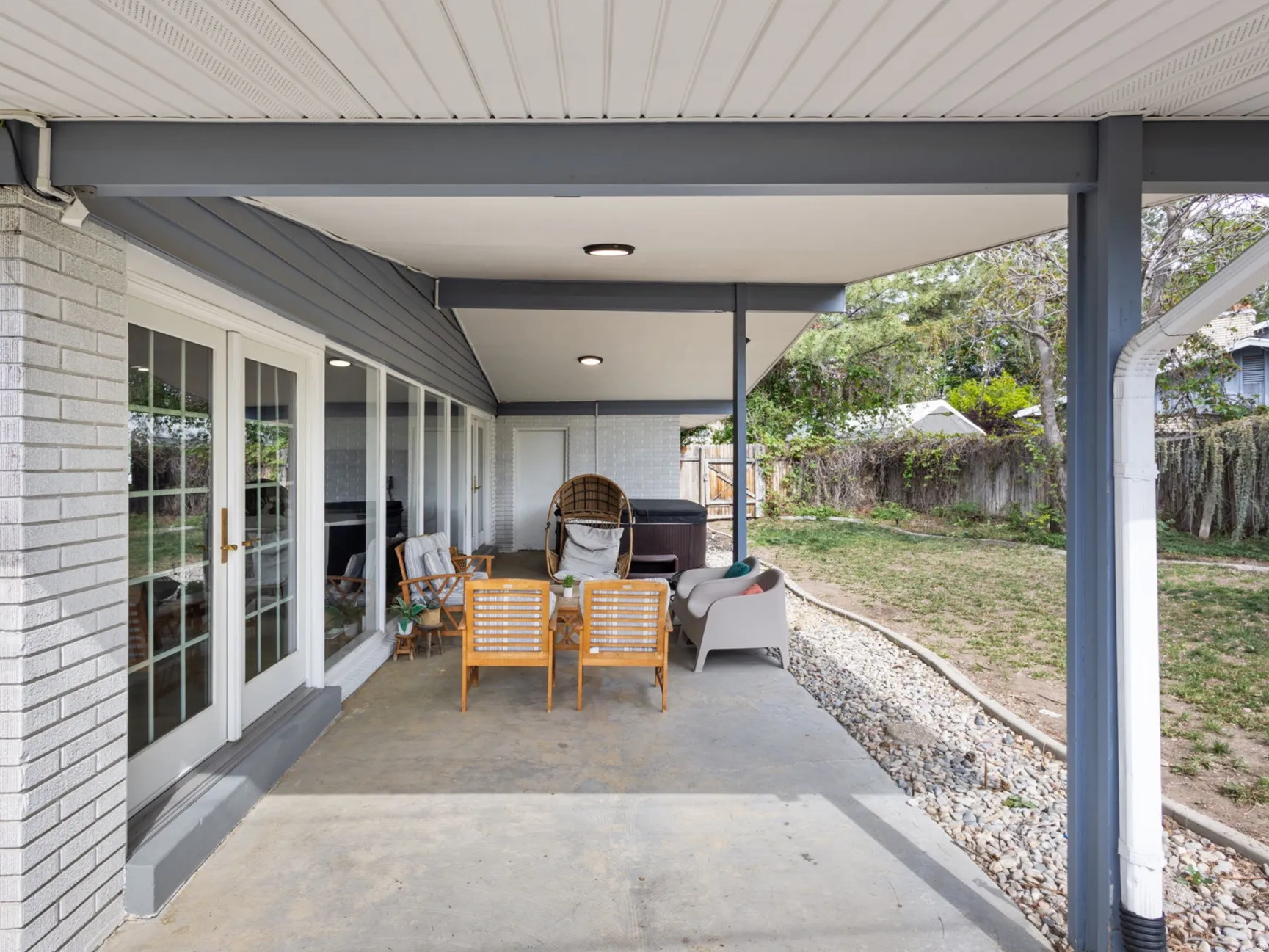 Expansive covered patio featuring a concrete surface, white brick exterior, and multiple French doors
