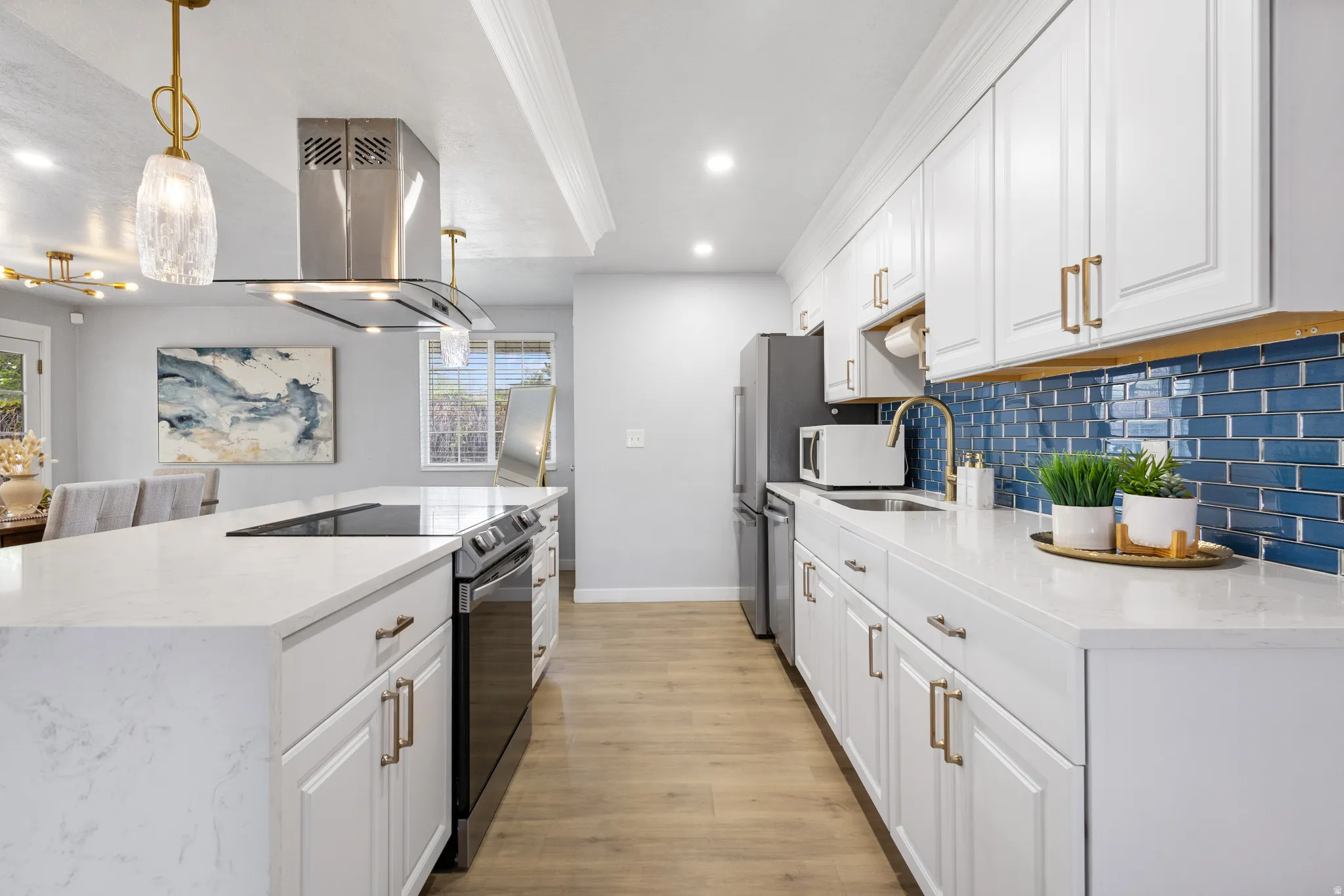 Kitchen featuring white shaker-style cabinetry, a blue subway tile backsplash, and light wood-finish flooring