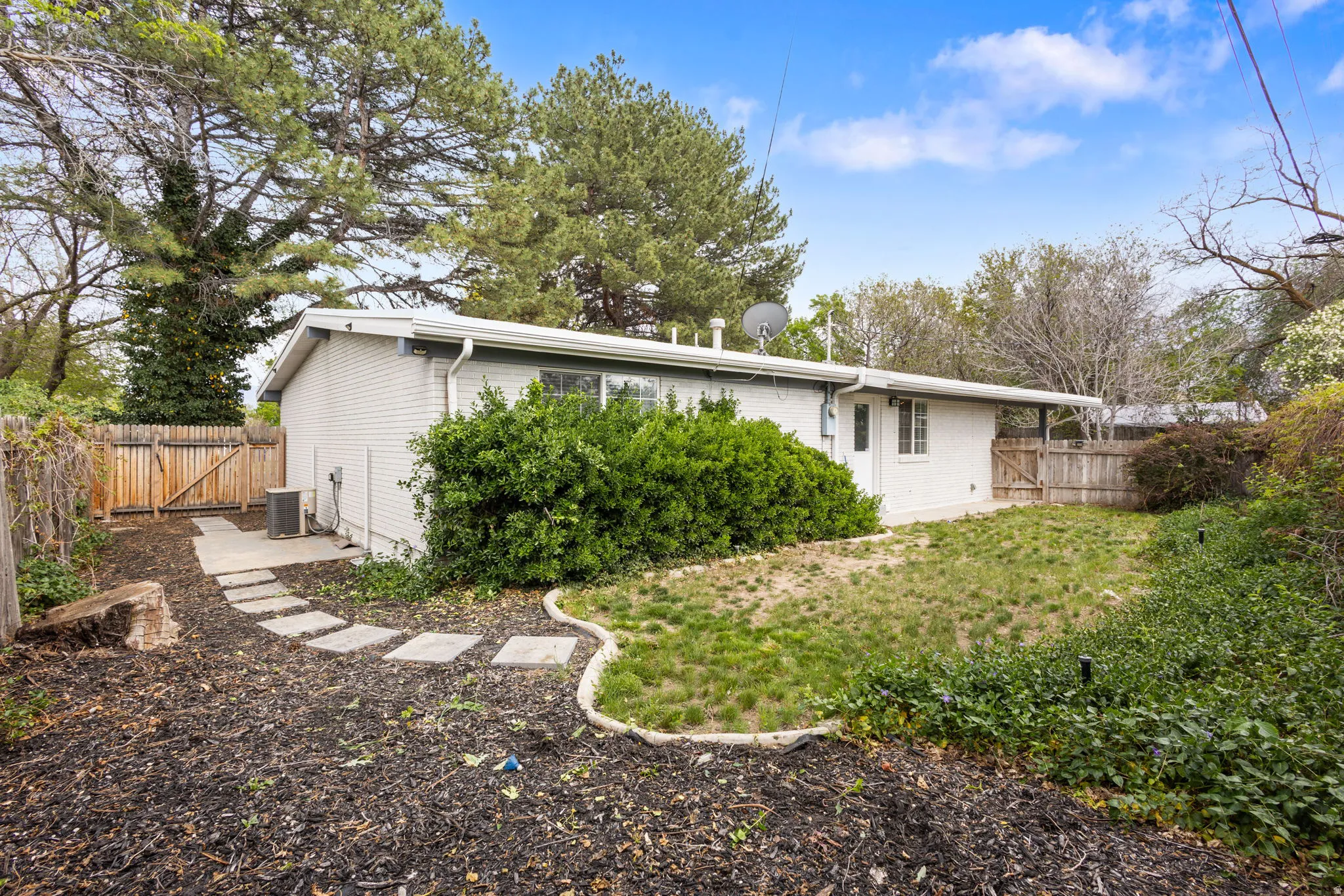 Rear exterior featuring a white brick facade, covered patio area, and a private fenced yard