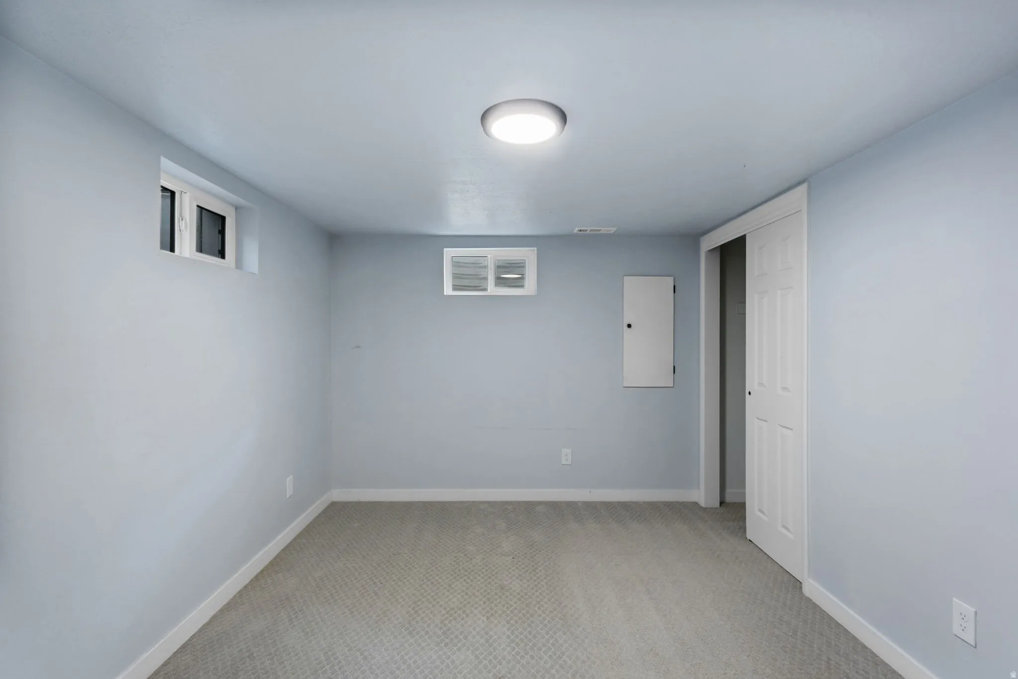 Spacious room with light gray carpeting, neutral wall color, and a flush-mount ceiling light