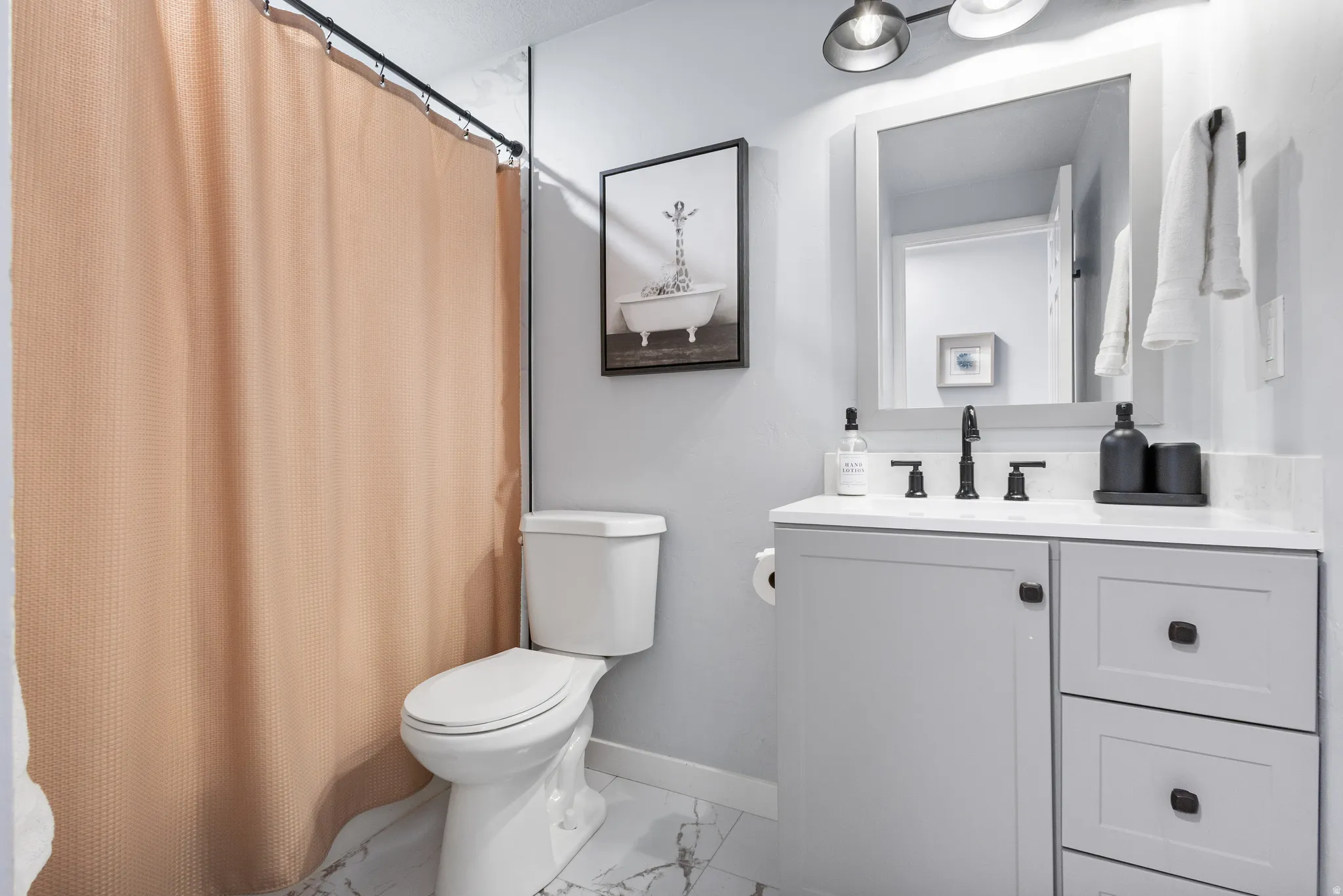 Bathroom vanity featuring a light gray cabinet with matte black hardware, white countertop, and matching framed mirror