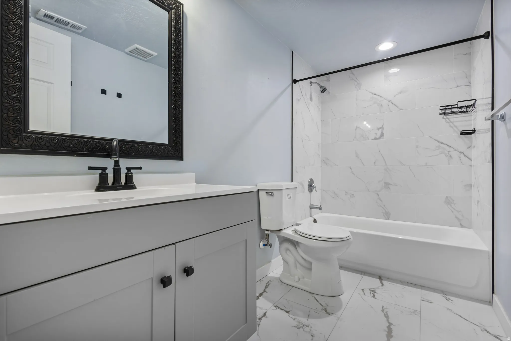 Bathroom featuring a white vanity with a white countertop, matte black faucet, and an ornate black framed mirror