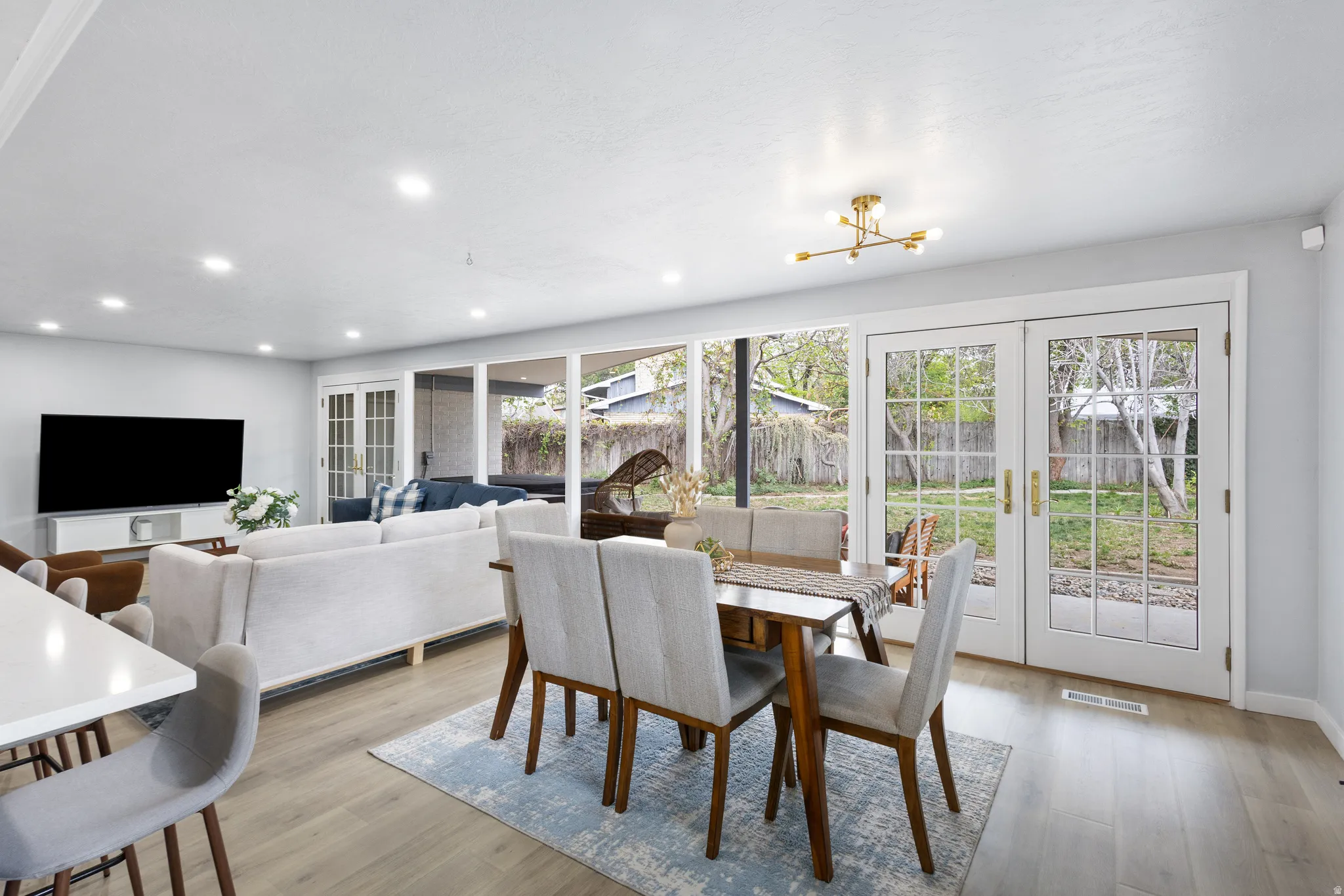 Open-concept living and dining area featuring wood-finish flooring, recessed lighting, and a modern chandelier