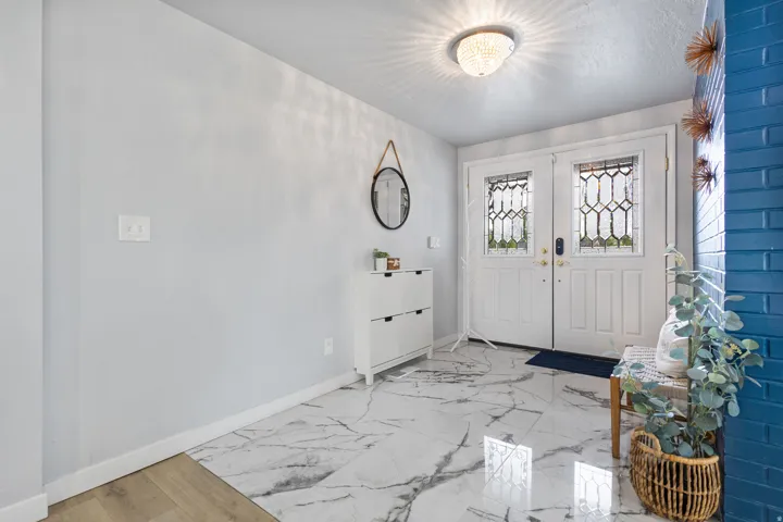 Entryway featuring double doors with decorative glass panels, a crystal flush mount ceiling light, and marble-look flooring