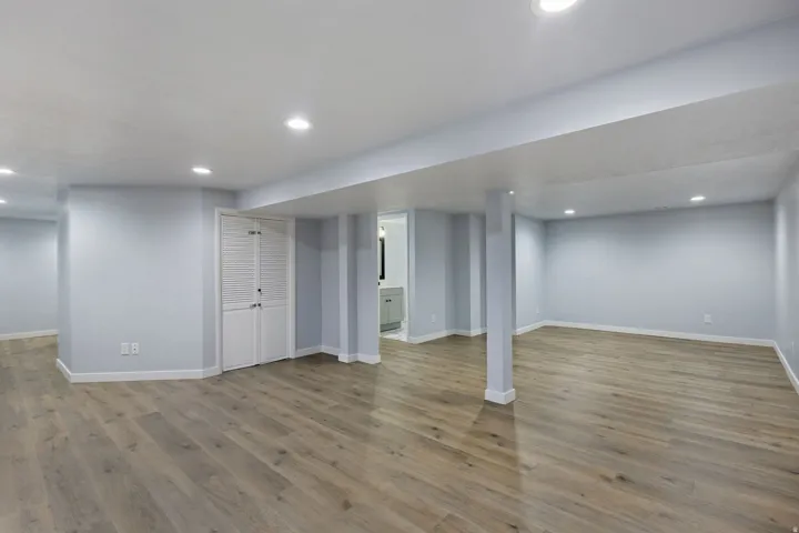 Spacious interior with wood-finish flooring, recessed lighting, light blue walls, and white baseboards
