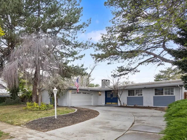 Mid-century modern residence featuring a two-car garage, concrete driveway, and gray siding with blue accent panels