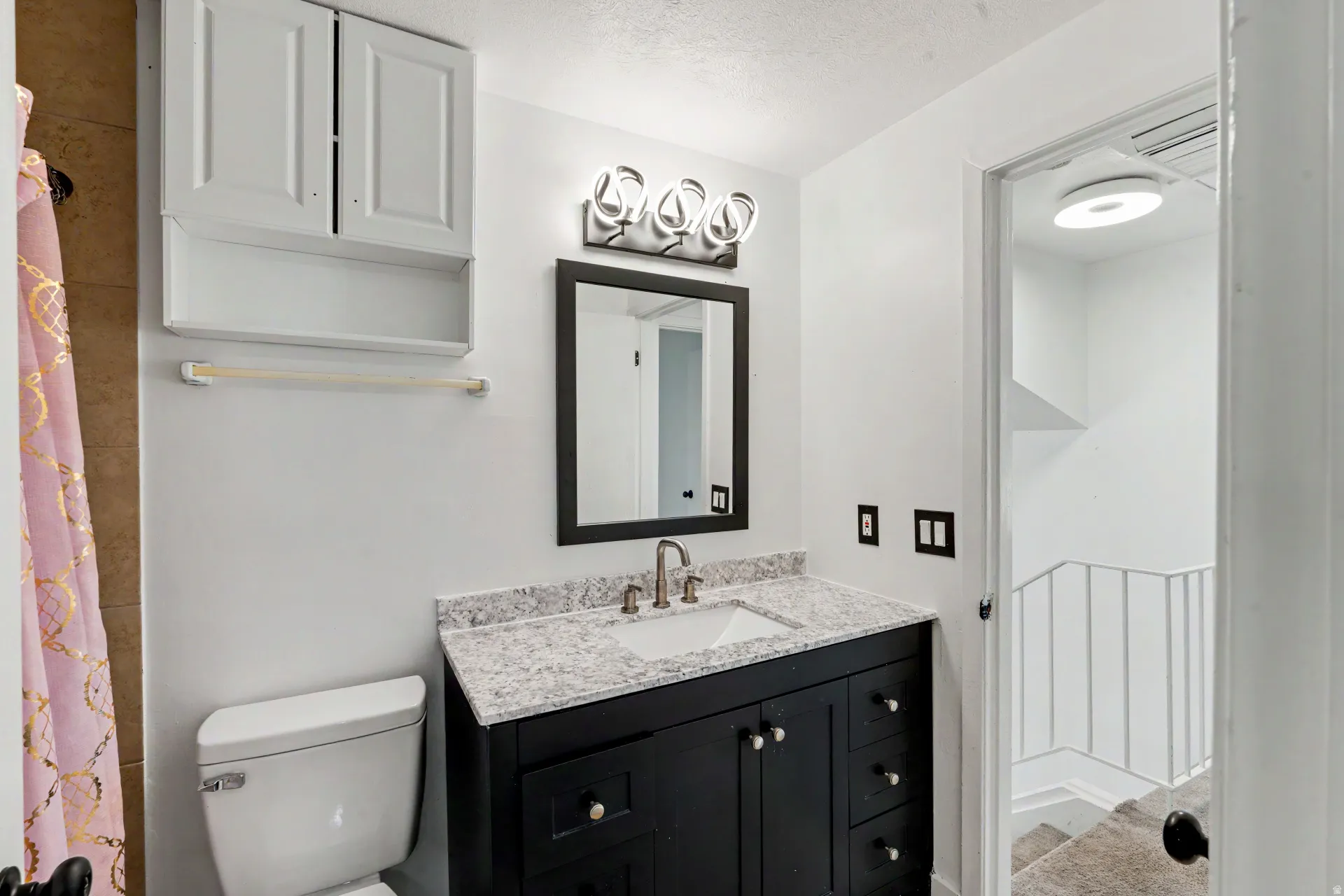 1st Bathroom upstairs vanity featuring a dark wood-finish base, integrated rectangular sink, and light-toned speckled countertop