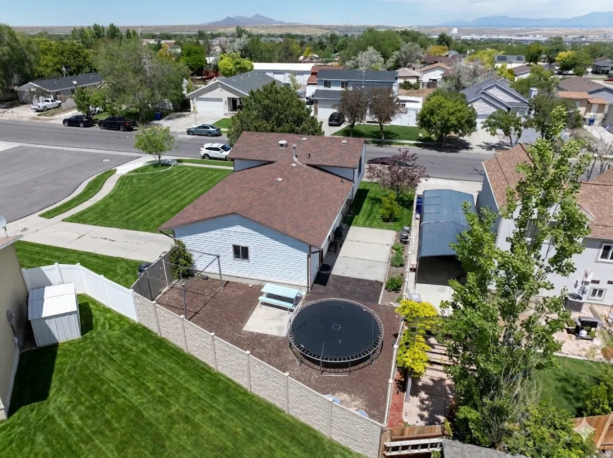Ai enhanced Aerial view of thel property featuring a white vinyl-sided structure with a brown shingle roof, a paved driveway, and an attached carport