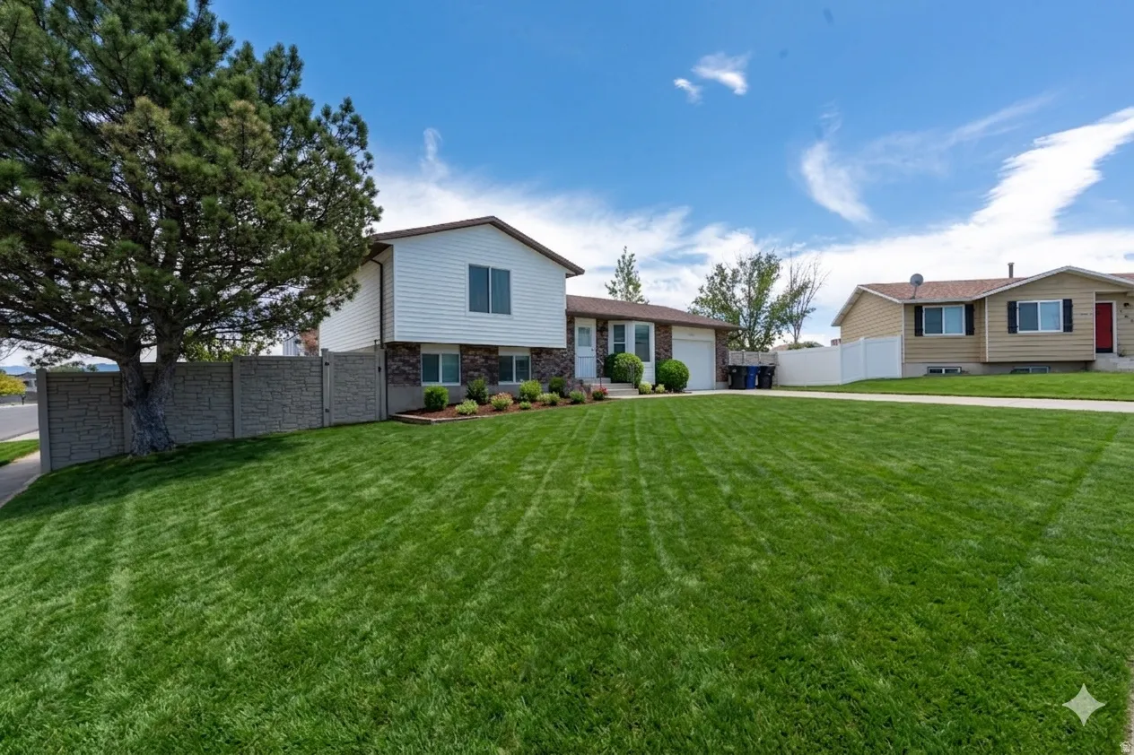 Ai enhanced side view of this Split-level residence featuring white siding and stone veneer accents
