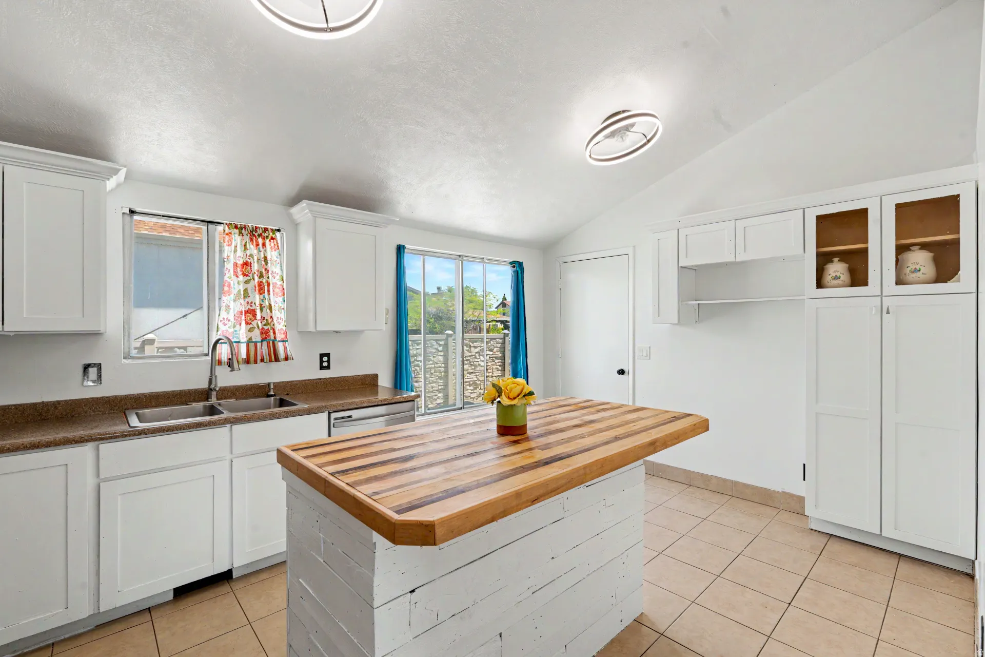Kitchen featuring white cabinetry, a butcher block island, tile flooring, and a stainless steel double basin sink