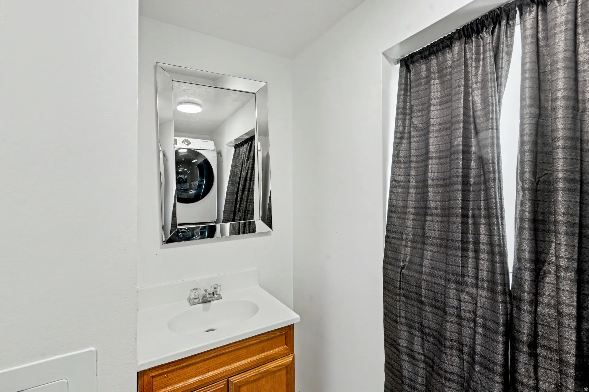 2nd bathroom downstairs with a white countertop and integrated sink, complemented by a large framed mirror