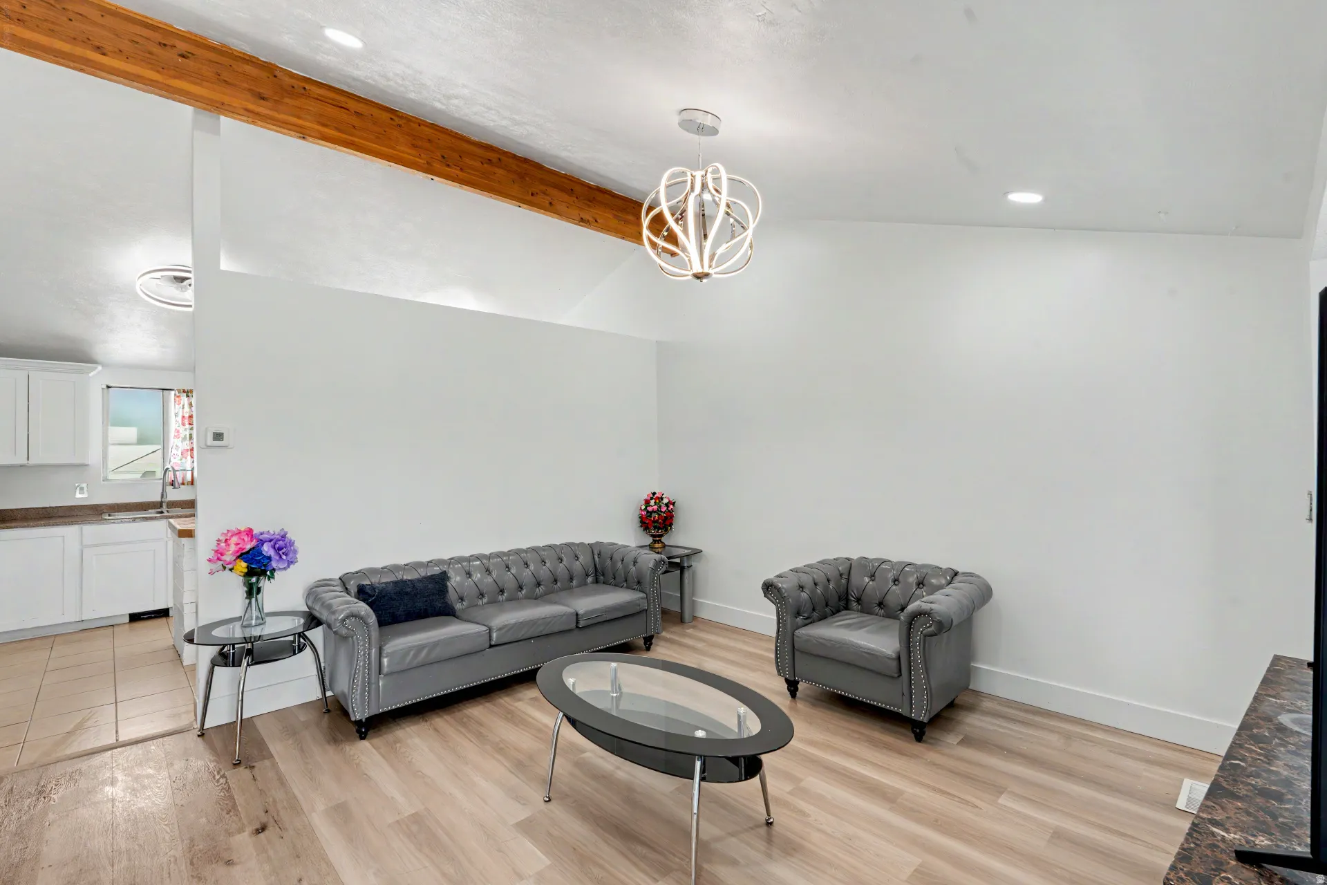 Vaulted ceiling featuring a prominent exposed wood beam and a contemporary chandelier