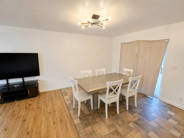 Dining area featuring a modern sputnik light fixture, light-toned walls, and mixed-material flooring with wood-finish planks and geometric tile patterns