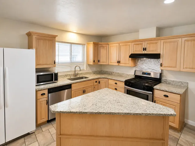 Kitchen featuring light wood cabinetry with crown molding, granite countertops, a stainless steel gas range, and a built-in dishwasher