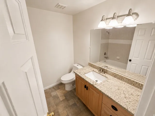 Bathroom vanity featuring a light-toned countertop, an undermount sink, and a brushed nickel faucet