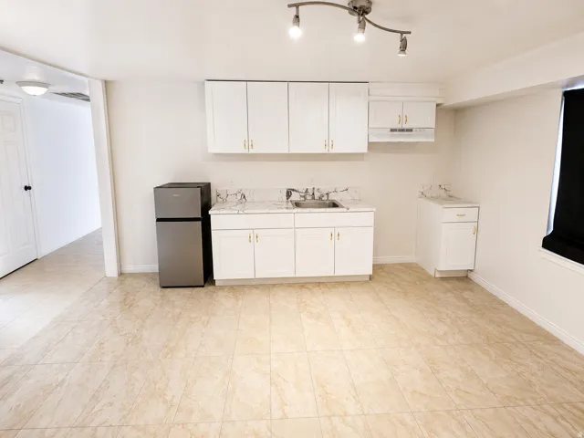 Kitchenette featuring white cabinetry, marble-look countertops, and a stainless steel compact refrigerator