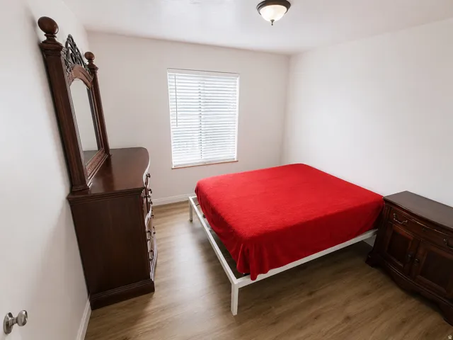Neutral wall tones, wood-finish flooring, and a window with blinds define this room