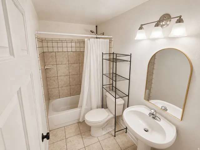 Pedestal sink with chrome faucet, arched mirror, and three-light vanity fixture