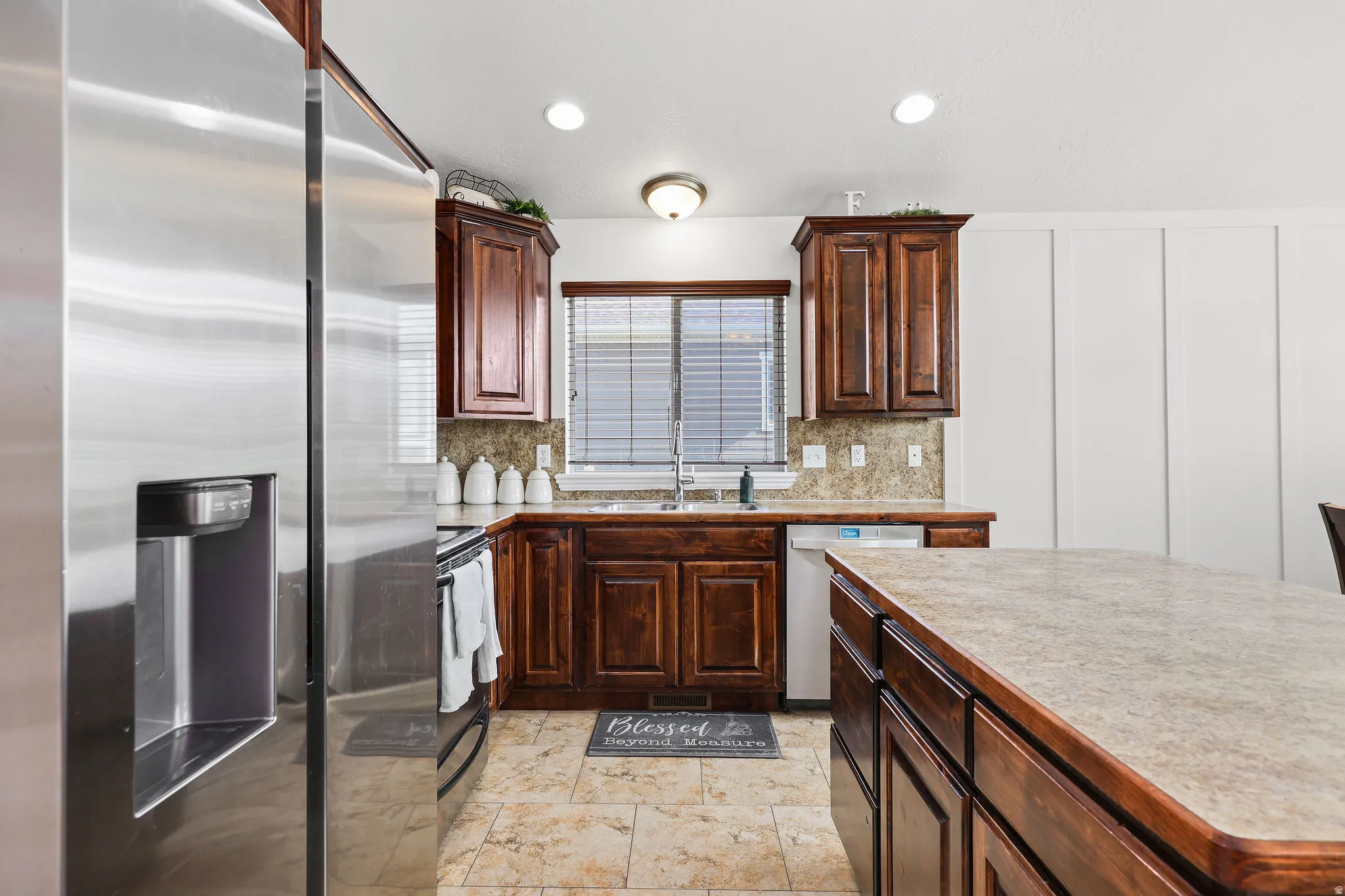 Kitchen featuring dark wood cabinetry, a stainless steel refrigerator, and a coordinating countertop