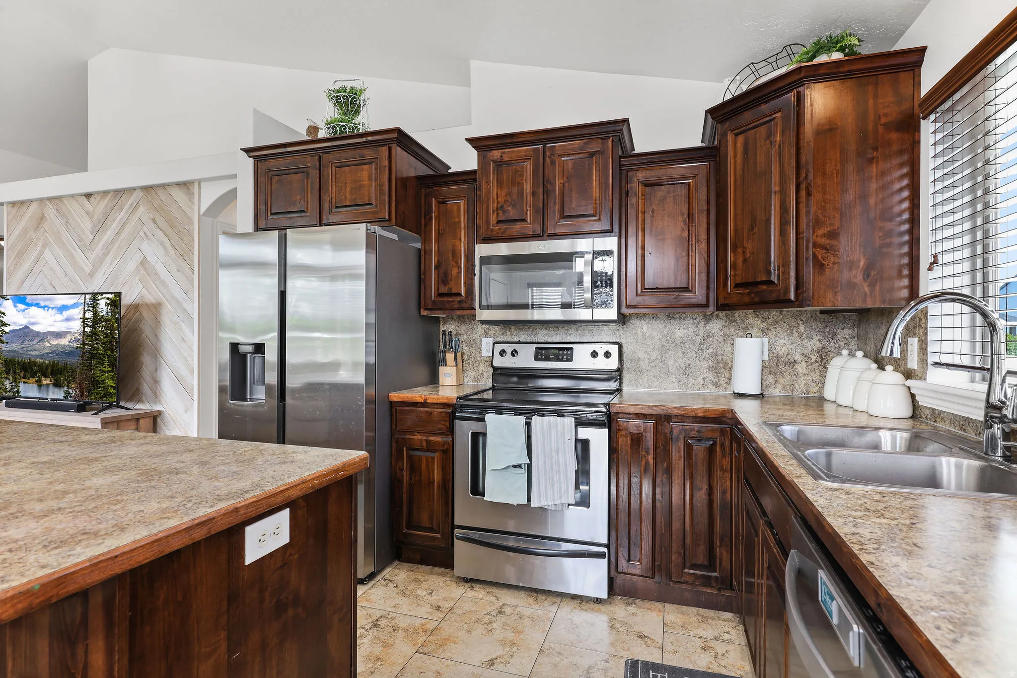 Kitchen with wood cabinetry, stainless steel appliances, and stone-look countertops