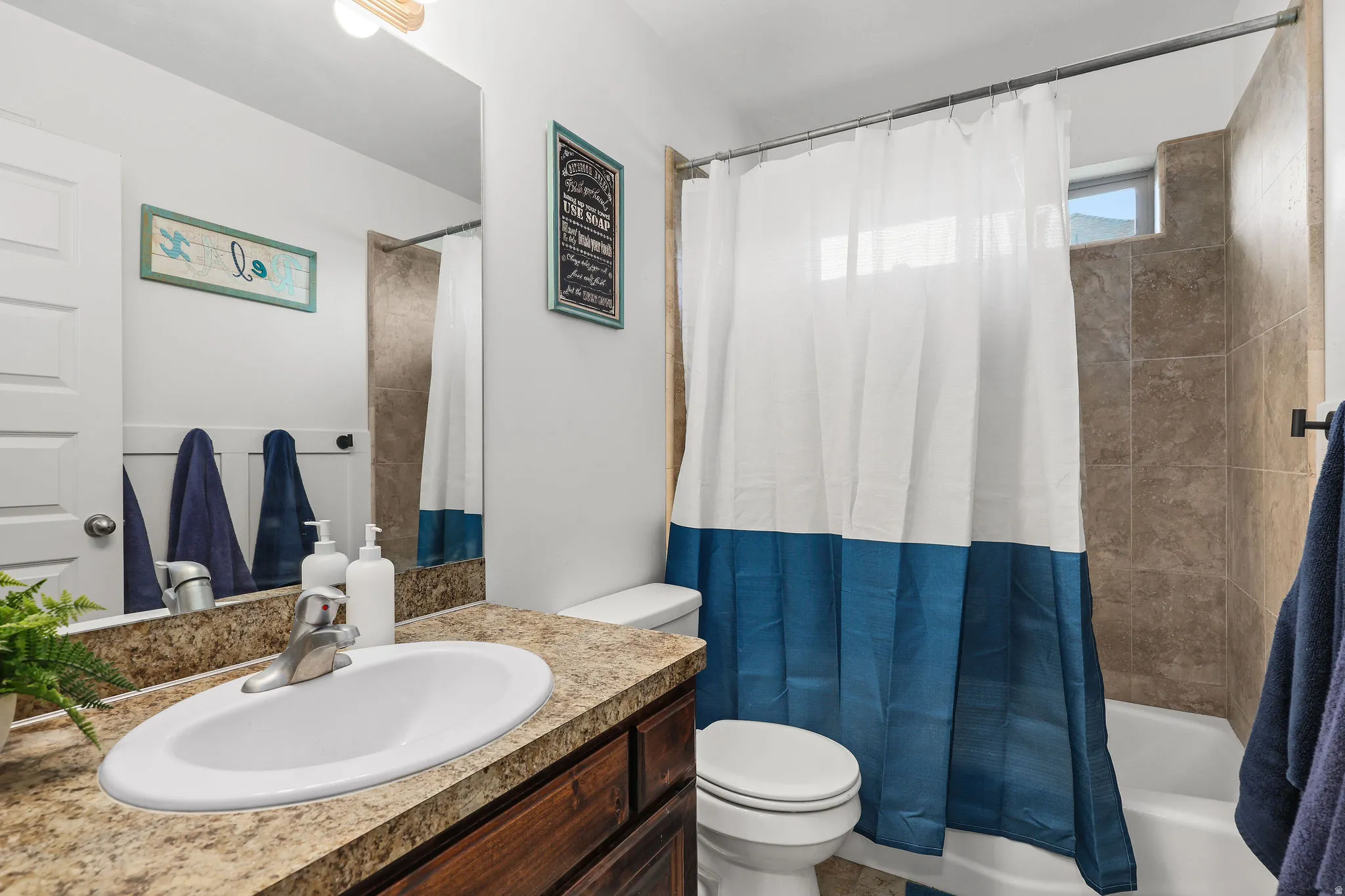 Bathroom featuring a wood-finish vanity with an integrated oval sink, a speckled countertop, and a large wall-mounted mirror