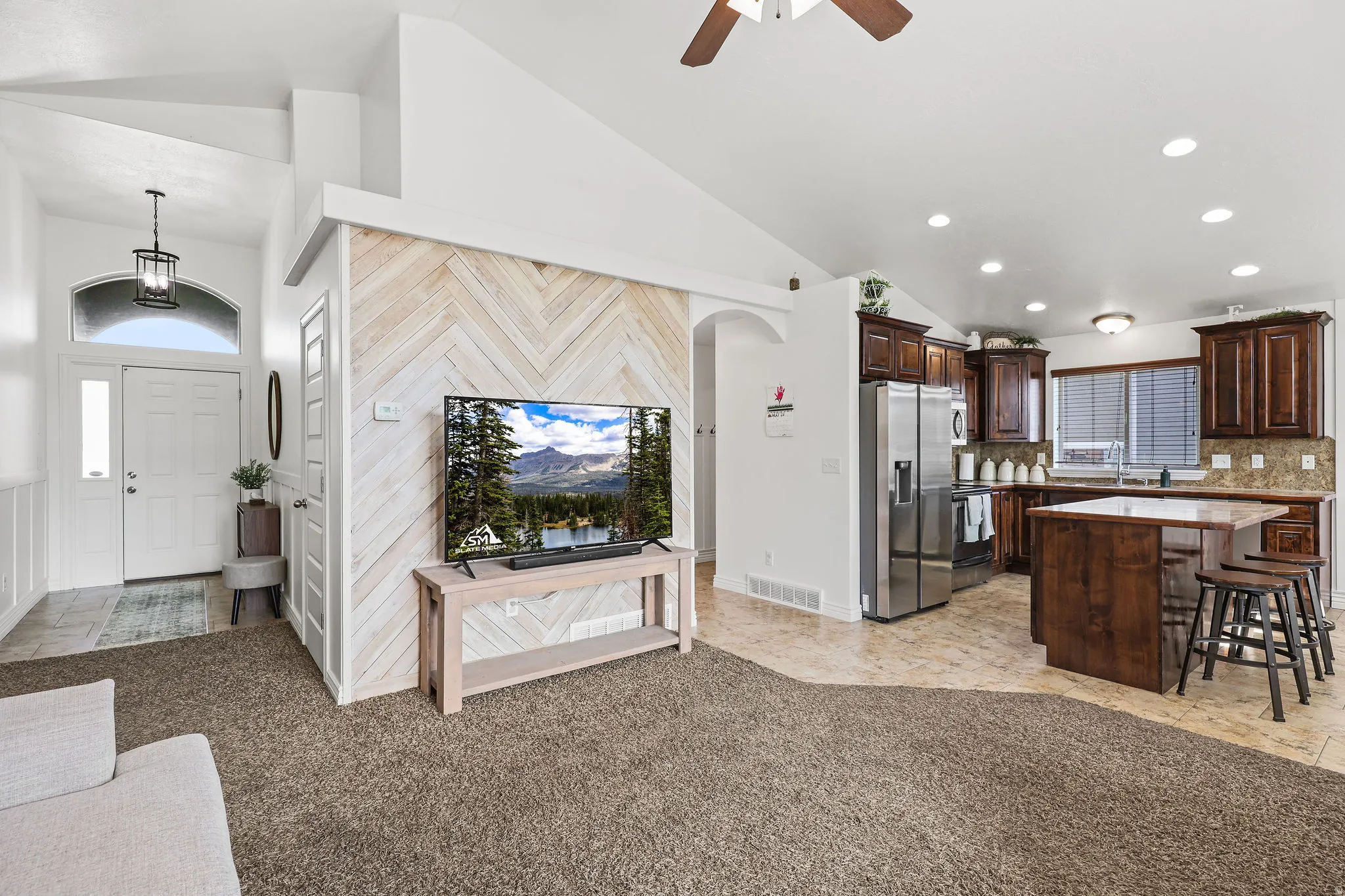 Open-concept living area with vaulted ceilings and a chevron wood-finish accent wall