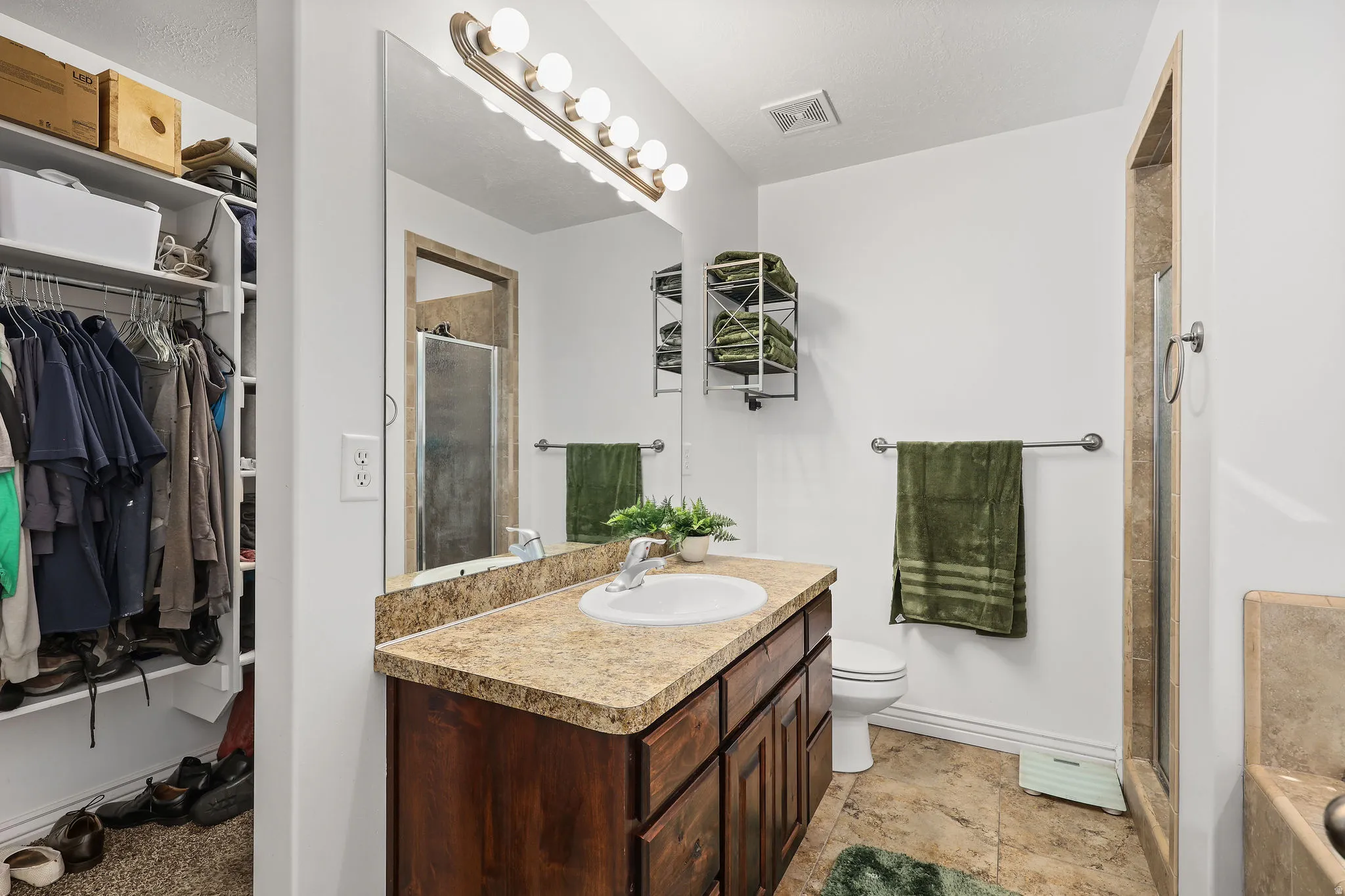 Bathroom featuring a single vanity with a stone-finish countertop, undermount sink, and wood-finish cabinetry