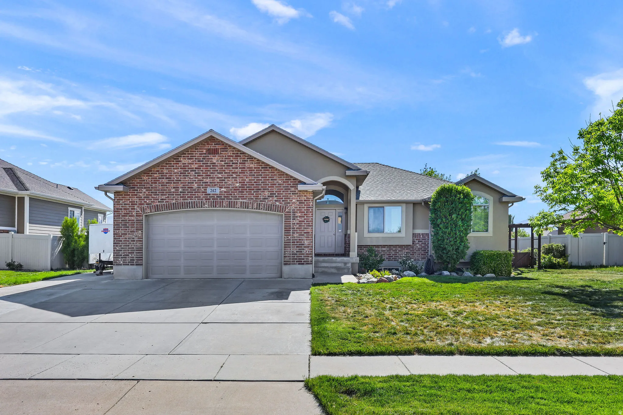 Brick and stucco facade featuring an arched entry, a two-car garage, and a concrete driveway