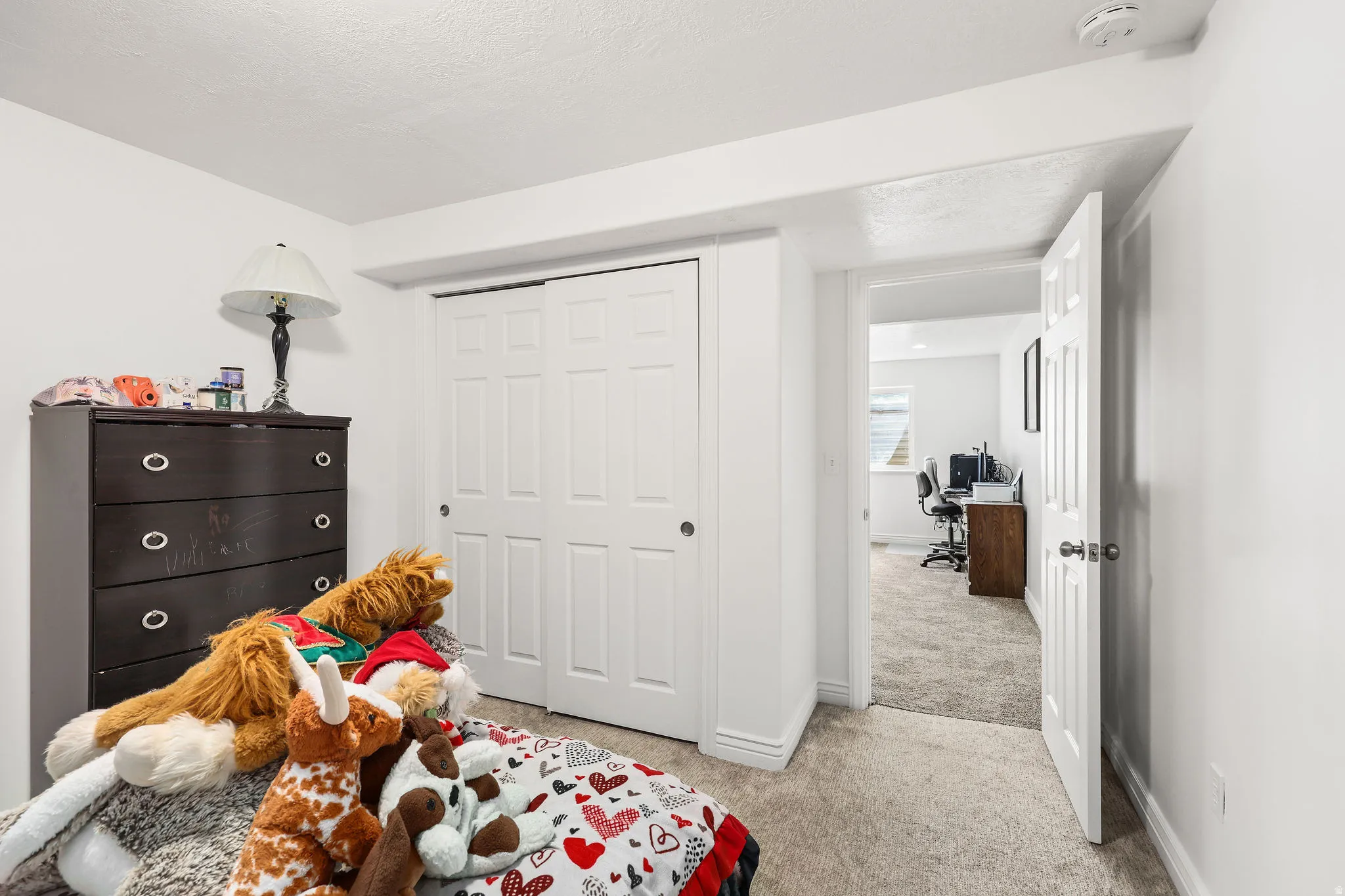 Carpeted interior room with white walls, a white bi-fold closet, and a doorway leading to another carpeted room