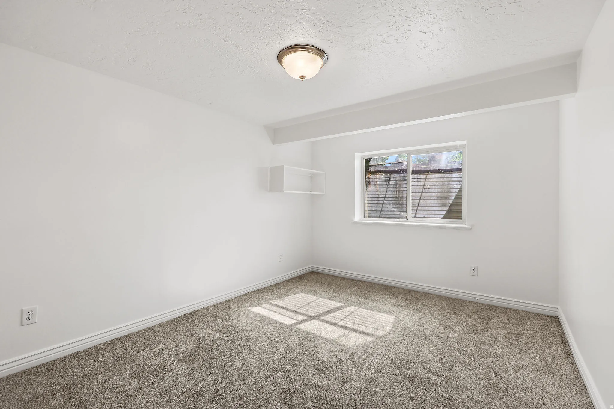 Interior room featuring neutral-toned carpet, white walls, and a single window