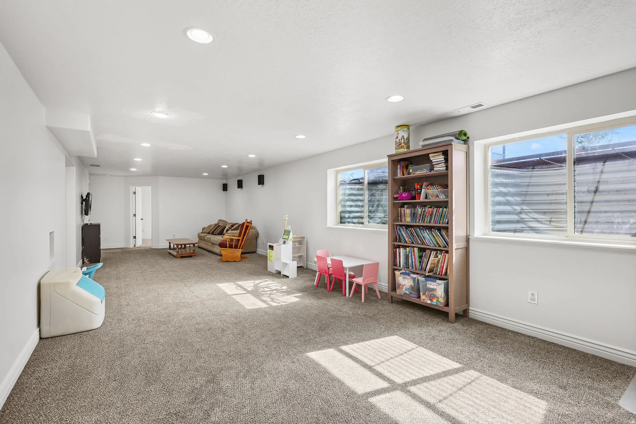 Spacious finished basement with recessed lighting, light gray carpeting, and two egress windows