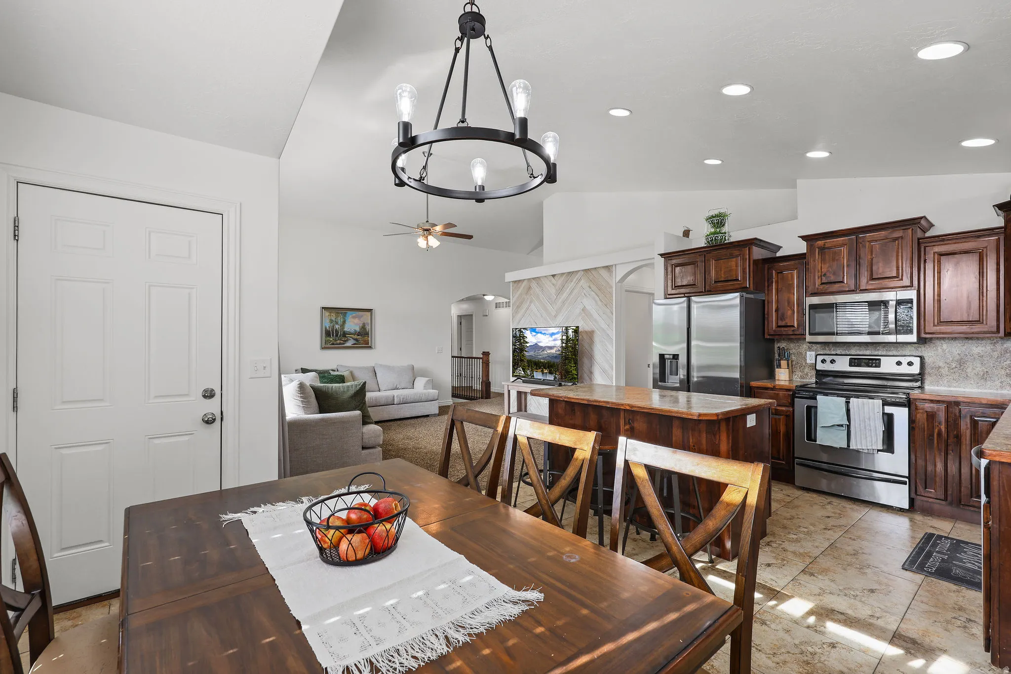 Expansive kitchen featuring wood-finish cabinetry, stainless steel appliances, and a central island with countertop seating