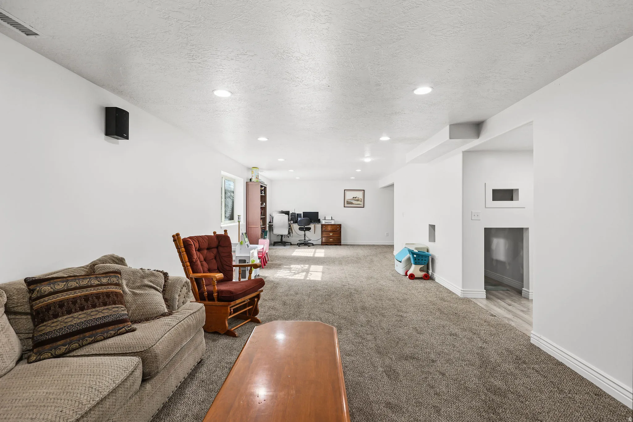 Spacious lower-level room featuring recessed lighting, light-toned carpeting, and white painted walls