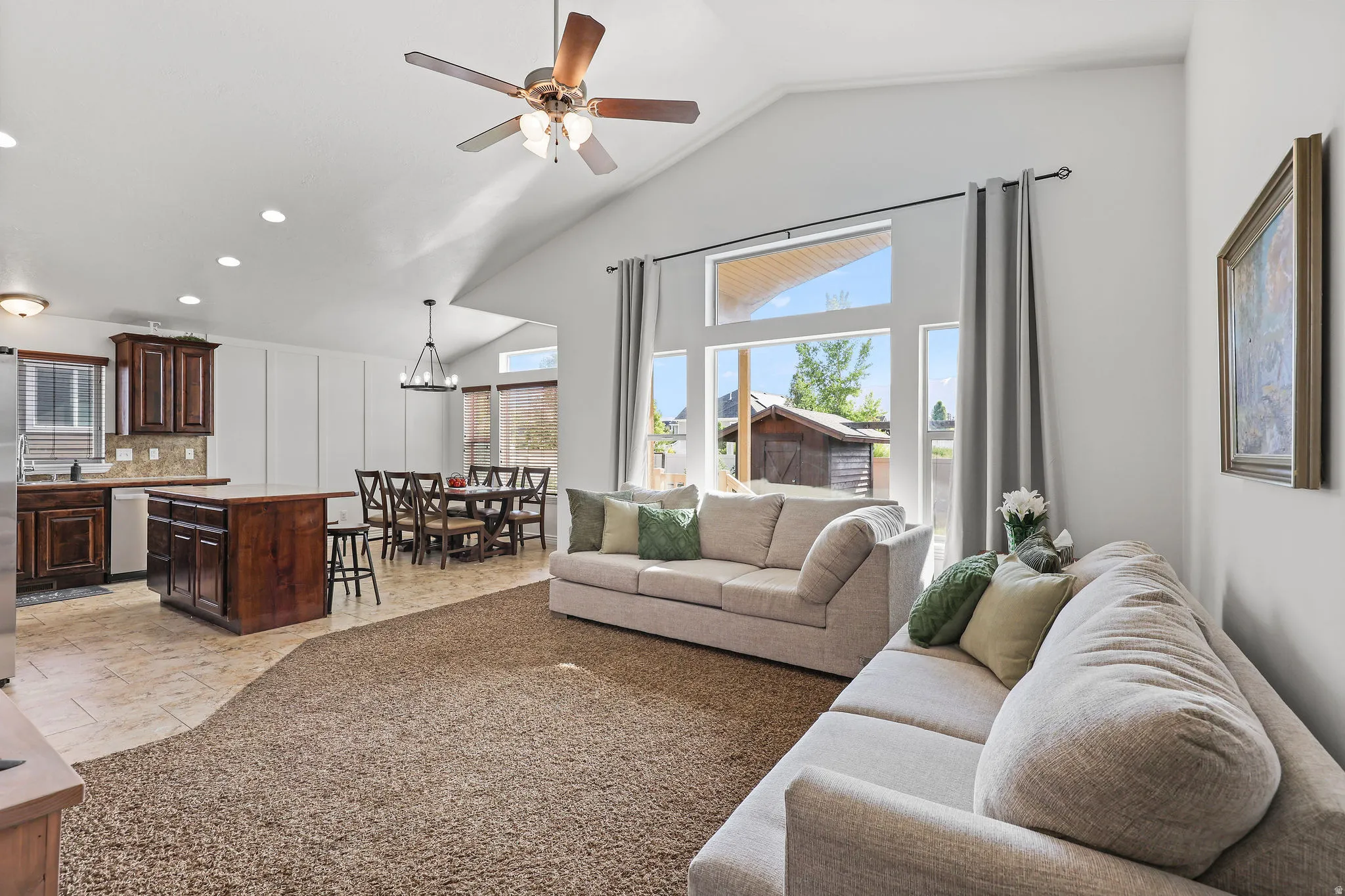 Vaulted ceilings accentuate the main living area, featuring a ceiling fan with integrated lighting