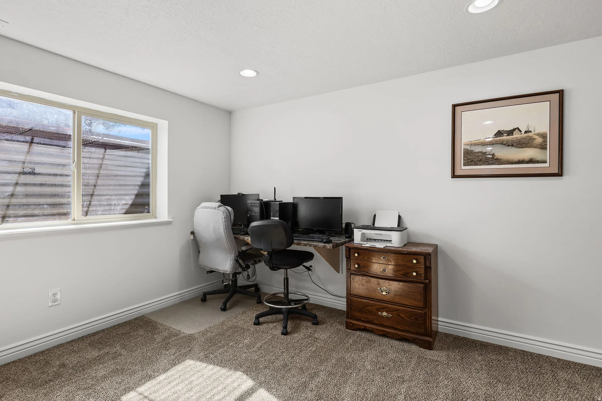 Carpeted room with a single window and recessed lighting