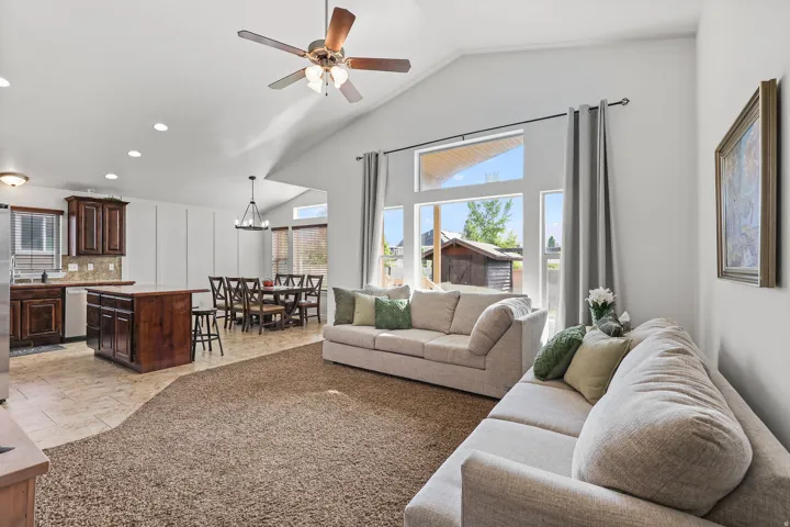 Vaulted ceilings accentuate the main living area, featuring a ceiling fan with integrated lighting