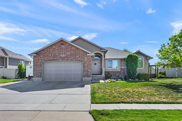 Brick and stucco facade featuring an arched entry, a two-car garage, and a concrete driveway